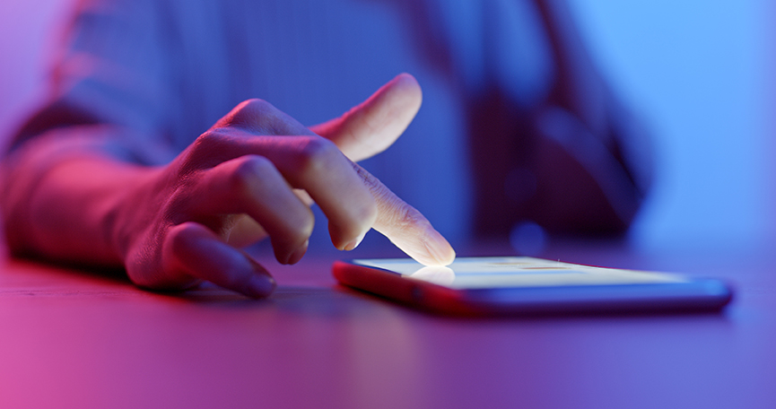 Finger tippt auf leuchtendes Smartphone-Display.