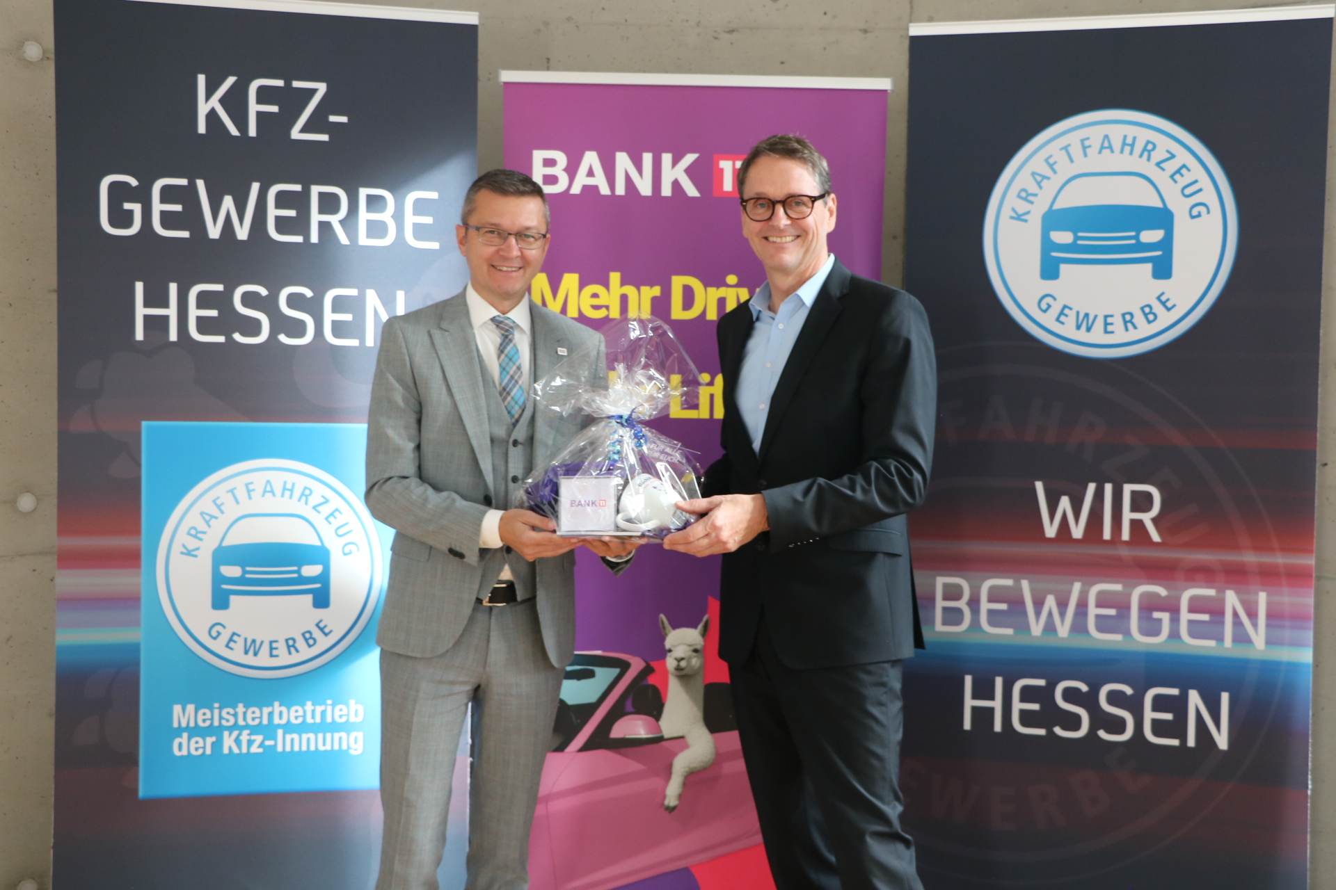 Vertreter von Bank11 und dem Kfz-Gewerbe Hessen bei einem Treffen mit Geschenkübergabe.